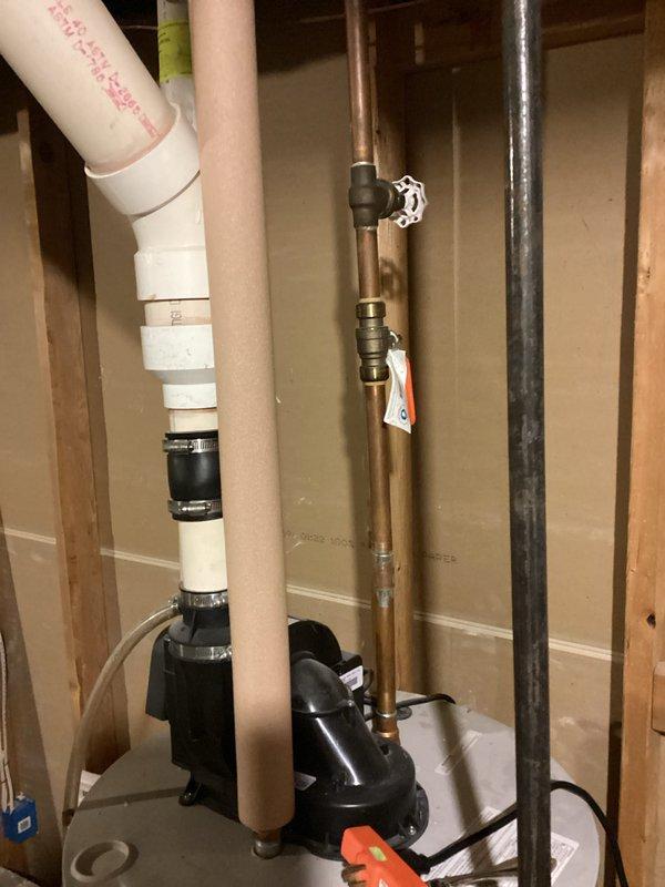 Responded to water heater issue with water accumulation in drain pan beneath 7-year-old unit that was still operational. Upon inspection, documented existing plumbing configuration including PVC drainage system, copper water lines, and associated connections. Photographed installation showing complex pipe routing with proper support brackets and multiple valve locations. Unit assessed for potential leaking, condensation buildup, or temperature/pressure relief valve discharge as possible sources of water in pan.