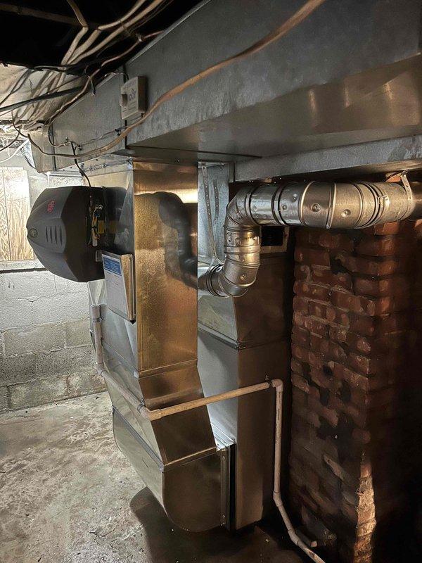 Completed full furnace replacement with installation of new Carrier gas furnace unit in residential basement location. Connected metallic supply ductwork with horizontal trunk line and elbow joint to existing distribution system. Installed unit against brick wall with proper clearances, secured all ductwork connections, verified proper venting, tested system operation, and confirmed heating functionality upon completion.