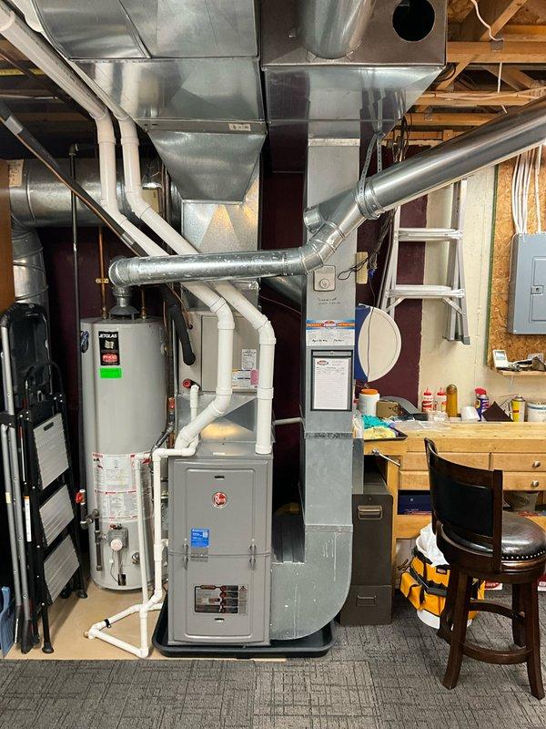 Provided estimate for replacement of 26-year-old Jetglas water heater located in basement mechanical room. Documented existing installation with associated plumbing connections, proximity to furnace and ductwork system, and current configuration of utility area to prepare comprehensive replacement quote.