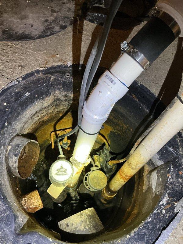 Responded to service call for non-operational sump pump causing basement dampness. Upon inspection, determined pump failure resulted from recent power surge damage. Verified sump basin, discharge piping with blue-handled valves, and PVC plumbing configuration. Documented existing single-pump system with yellow submersible pump in concrete basin. Provided estimate for battery backup sump pump system installation to prevent future power outage failures and protect against water intrusion.