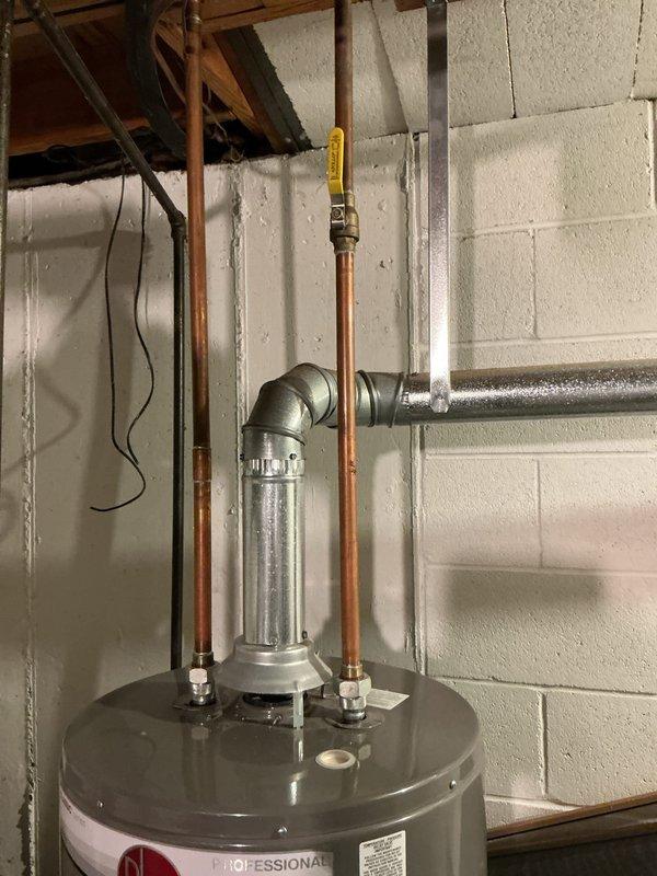 Completed water heater replacement estimate for residential property with 11-year-old existing unit installed in basement utility area. Assessed current gray cylindrical tank water heater with copper supply lines, galvanized fittings, and yellow-handled shut-off valve mounted against concrete block wall. Documented existing installation including vertical copper piping with elbow joints, horizontal galvanized distribution lines, and proximity to HVAC ductwork system. Evaluated accessibility for replacement, existing plumbing connections, venting requirements, and clearances around unit. Provided comprehensive estimate for new water heater installation including removal and disposal of existing unit, installation of replacement tank with proper code-compliant connections, and necessary modifications to accommodate new equipment specifications.