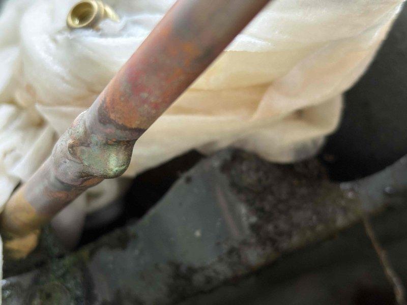 Responded to recurring no-cooling complaint on 3-year-old EnergiAir unit. Upon inspection, discovered severely corroded copper refrigerant line with significant oxidation and green verdigris buildup at connection joints, indicating long-term moisture exposure and deterioration. The extensive corrosion at pipe fittings was identified as the root cause of the chronic cooling failure. Documented the failed components with photographs showing compromised pipe integrity and recommended complete refrigerant line replacement to permanently resolve the ongoing cooling issues that have required multiple service calls.