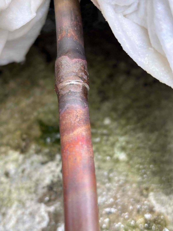 Responded to recurring no-cooling complaint on 3-year-old EnergiAir unit. Upon inspection, discovered severely corroded copper refrigerant line with significant oxidation and green verdigris buildup at connection joints, indicating long-term moisture exposure and deterioration. The extensive corrosion at pipe fittings was identified as the root cause of the chronic cooling failure. Documented the failed components with photographs showing compromised pipe integrity and recommended complete refrigerant line replacement to permanently resolve the ongoing cooling issues that have required multiple service calls.