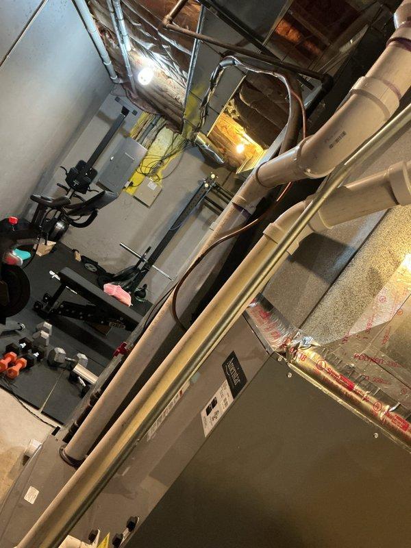 Rerouted furnace exhaust piping system in basement mechanical room to correct improper venting configuration. Installed new white PVC exhaust pipes with proper support brackets and purple mounting straps, ensuring code-compliant vertical and horizontal runs with appropriate pitch for condensate drainage. System tested and verified operational upon completion.