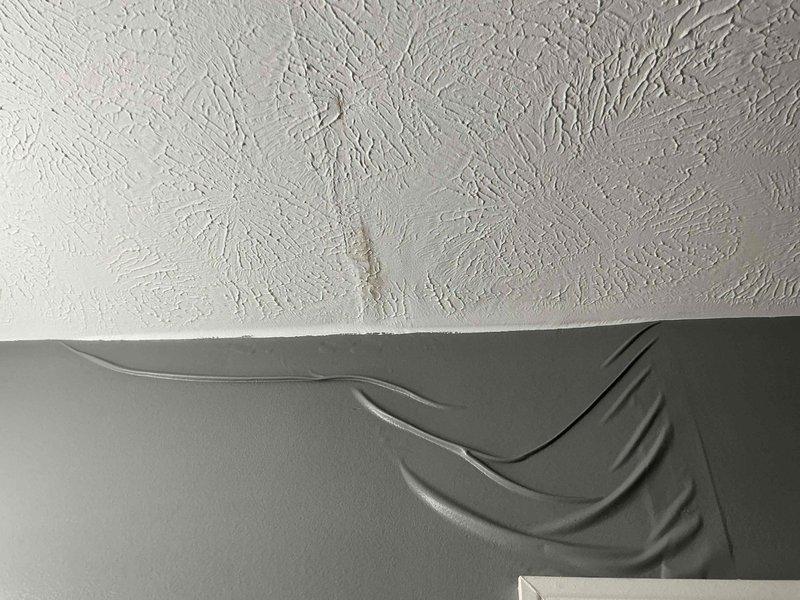 Responded to plumbing leak reported from upstairs floor with water intrusion visible below. Created ceiling access opening to expose and inspect plumbing infrastructure above bathroom vanity area. Located source of leak in overhead piping system, including PVC and metal supply lines. Documented conditions through photographs showing exposed framing, pipe configuration, and leak origin point for repair assessment and future reference.