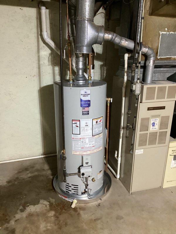Successfully installed a 40-gallon natural gas water heater (6-year warranty, short model) in basement utility room. Completed all plumbing connections using copper and galvanized steel piping with proper fittings and elbows, secured vertical copper lines with metal support straps, and ensured proper venting configuration. Unit installed adjacent to existing HVAC furnace with all connections tested and verified operational.