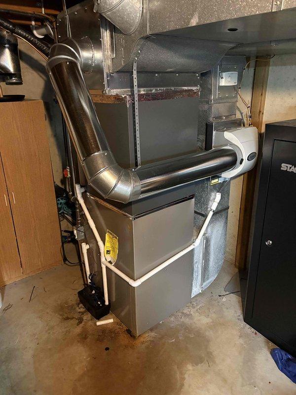 Completed full air conditioning system replacement at residential property. Removed existing outdoor condensing unit and installed new unit on concrete pad against exterior wall with proper clearances maintained. Indoor air handler connected to existing ductwork system in basement utility area with new refrigerant lines, condensate drainage via PVC piping, and electrical connections completed to manufacturer specifications. System tested and verified operational.