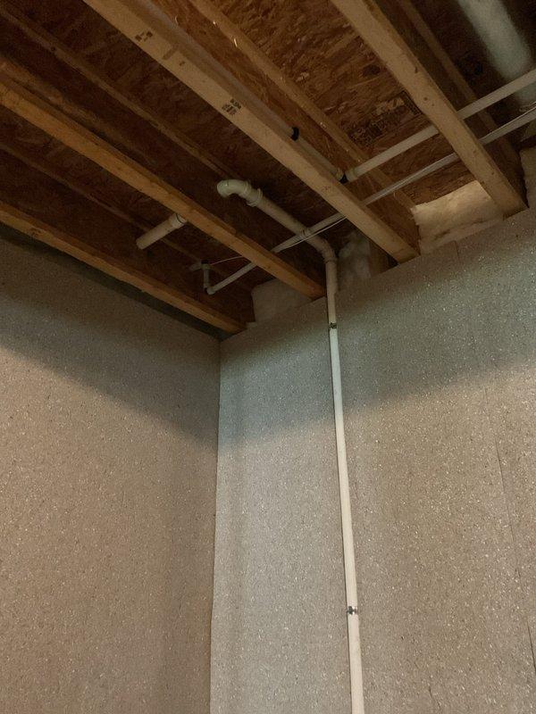 Performed routine sump pump maintenance including inspection of discharge piping system running from basement through exterior wall. Verified proper operation of pump mechanism visible through exterior wall access panel and confirmed secure mounting of brass discharge fitting with rubber coupling connections. Inspected white PVC discharge line routing from pump location up through basement ceiling joists with proper elbow joint installation for horizontal run, ensuring adequate drainage flow and no blockages in the system.