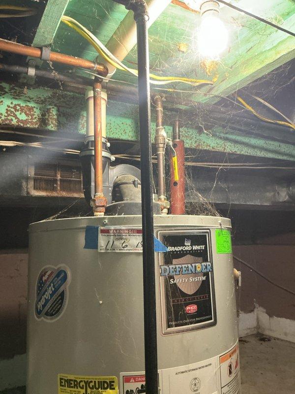 Responded to service call for non-operational Honeywell water heater with 7-flash error code in flooded basement. Upon arrival, found 9-year-old unit with standing water around base. The 7-flash diagnostic code indicated a gas control valve failure requiring immediate attention. Assessed both the primary water heater and adjacent Bradford White unit for flood damage. Documented equipment condition, manufacturer labels, and installation configuration including copper supply lines, gas piping, and venting system. Photographed EnergyGuide labels, control assemblies, and basement utility area showing water damage on concrete floor. Recommended gas valve replacement or full unit replacement based on age and flood exposure to electrical components and insulation.