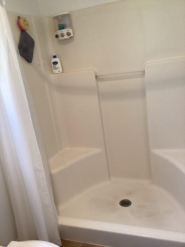Conducted comprehensive plumbing assessment for bathroom remodel project, documenting existing fiberglass shower stall installation with integrated shelving system and center drain configuration. Evaluated under-sink plumbing infrastructure including P-trap assembly, PVC drain lines, and supply connections to determine scope of work required for renovation project.