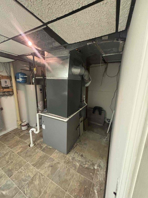 Completed full air conditioning system replacement in residential basement utility room. Installed new furnace unit with integrated cooling coil, connected metallic supply ductwork and plenum assembly, and ran refrigerant lines to outdoor condensing unit. Established proper PVC condensate drainage and venting, verified all electrical connections to panel, and tested system operation for proper airflow and temperature output.