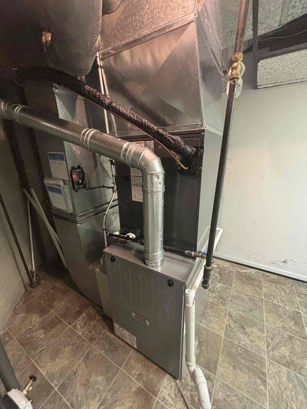 Completed full air conditioning system replacement in residential basement utility room. Installed new furnace unit with integrated cooling coil, connected metallic supply ductwork and plenum assembly, and ran refrigerant lines to outdoor condensing unit. Established proper PVC condensate drainage and venting, verified all electrical connections to panel, and tested system operation for proper airflow and temperature output.