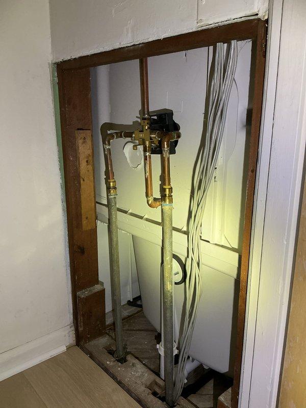 Addressed low water pressure affecting both hot and cold water supply to bathroom fixtures including tub and sink. Accessed plumbing system through wall panel to inspect supply lines and pressure regulation components. Diagnosed sediment buildup in aging galvanized pipes consistent with historical hard water conditions in 50-year-old residential plumbing system. Inspected pressure regulator, shut-off valves, and supply line connections for blockages and flow restrictions. Documented existing plumbing configuration including copper fittings and brass valve assemblies. Cleaned aerator and drain assembly in sink fixture, removing accumulated mineral deposits and debris. Provided recommendations for long-term resolution of sediment-related pressure issues in aging pipe infrastructure.