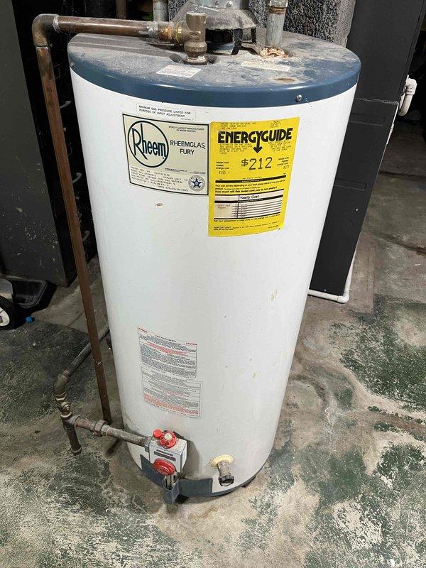Completed water heater estimate for residential property. Assessed existing Rheem Rheemglas Fury electric water heater showing signs of age with copper piping patina, floor staining around base, and standard safety valve configuration. Documented current installation including plumbing connections, venting system with PVC and metallic ductwork, and utility room conditions to provide replacement recommendations and specifications.
