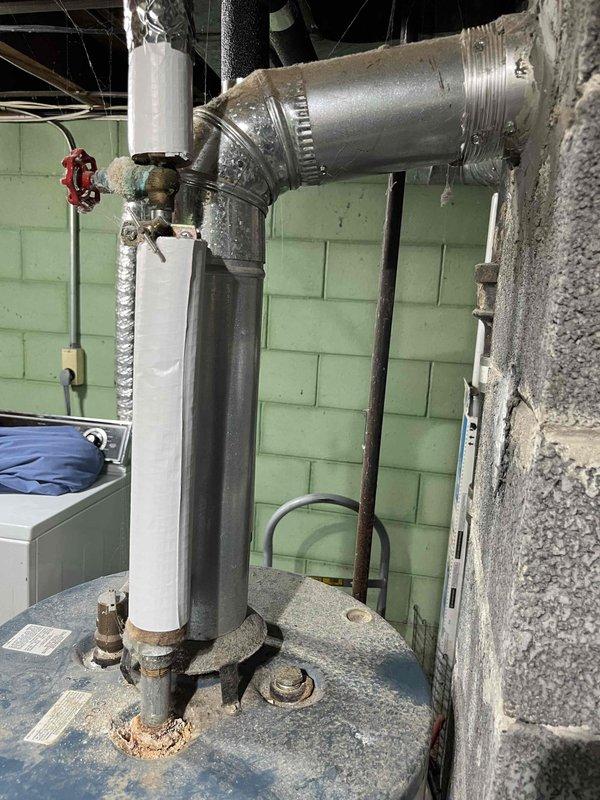 Completed water heater estimate for residential property. Assessed existing Rheem Rheemglas Fury electric water heater showing signs of age with copper piping patina, floor staining around base, and standard safety valve configuration. Documented current installation including plumbing connections, venting system with PVC and metallic ductwork, and utility room conditions to provide replacement recommendations and specifications.