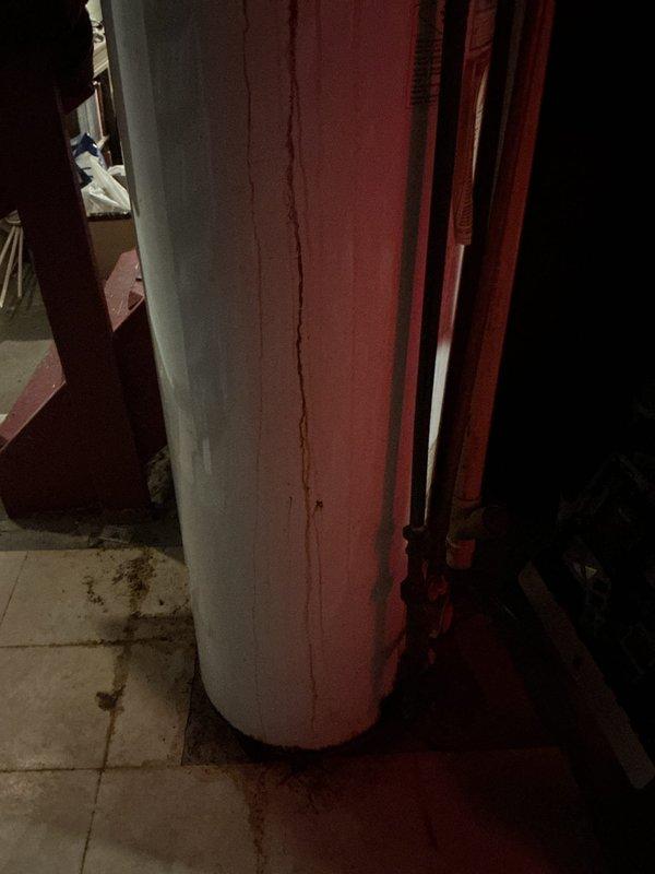 Provided estimate for replacement of thirty-year-old water heater showing significant rust staining and deterioration. Unit exhibits visible corrosion on exterior surfaces and rust accumulation at base, indicating end of serviceable life expectancy. Documented existing installation conditions including plumbing connections and utility space configuration for replacement planning.