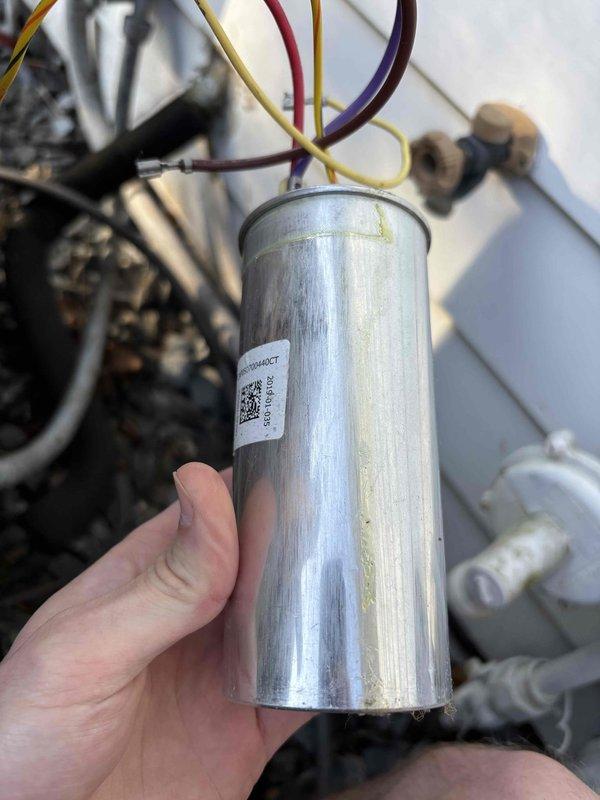 Completed annual cooling maintenance on EnergiAir system under 5-year warranty coverage. Identified failed dual-run capacitor showing visible corrosion and moisture damage on exterior casing. Disconnected defective capacitor from compressor and condenser fan motor circuits, replaced with new OEM-spec capacitor, and reconnected all terminal connections. Verified proper wire routing and secure spade terminal attachments. System tested and operating within normal parameters following component replacement.