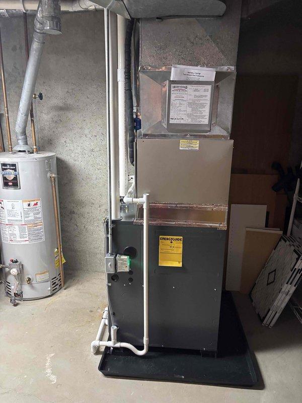 Completed full furnace installation in basement utility area. Installed new vertical furnace unit with proper ductwork connections, PVC condensate drainage piping, and venting system. All equipment positioned on concrete floor with adequate clearance for maintenance access, system tested and operational.
