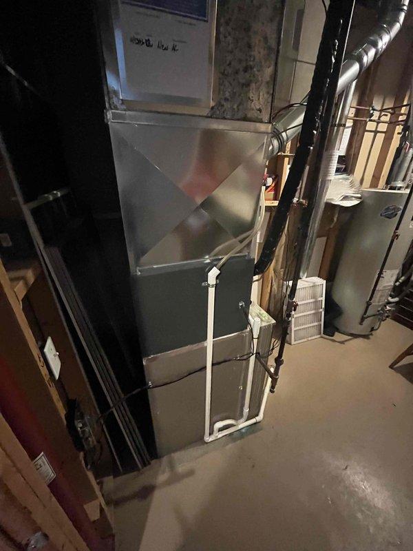 Complete air conditioning system replacement performed in residential basement mechanical room. Installed new air handler unit with proper mounting and connections to existing ductwork infrastructure. Configured metallic flexible supply ductwork with appropriate insulation wrapping and secured all connections. Installed PVC condensate drain lines and established electrical connections including conduit routing and wiring terminations. Verified proper integration with existing copper refrigerant lines and completed all necessary system connections. All components mounted to code specifications with proper clearances maintained. System tested and operational upon completion.