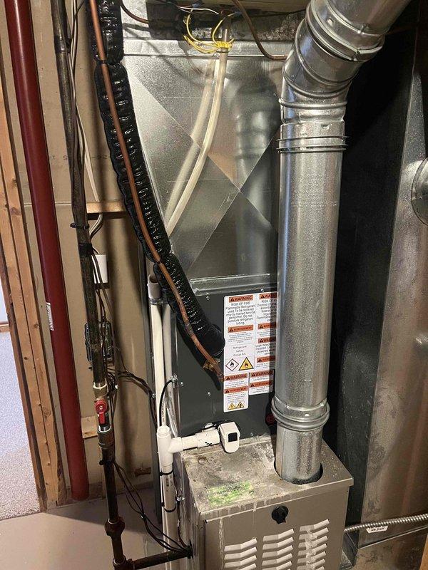 Complete air conditioning system replacement performed in residential basement mechanical room. Installed new air handler unit with proper mounting and connections to existing ductwork infrastructure. Configured metallic flexible supply ductwork with appropriate insulation wrapping and secured all connections. Installed PVC condensate drain lines and established electrical connections including conduit routing and wiring terminations. Verified proper integration with existing copper refrigerant lines and completed all necessary system connections. All components mounted to code specifications with proper clearances maintained. System tested and operational upon completion.