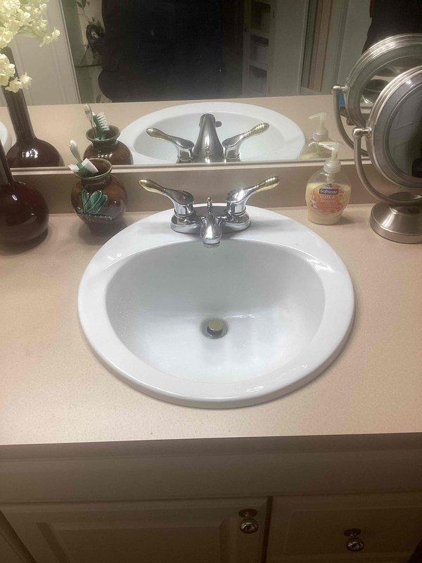 Responded to service call for low hot water pressure issues in kitchen and shower following recent water heater installation. Inspected bathroom vanity faucet with chrome two-handle fixture and verified proper drainage operation. Assessed kitchen faucet cartridge condition to address pressure concerns and evaluated basement drain clog. Documented existing plumbing fixtures and conditions with photographic evidence for reference. Recommended cartridge replacement for kitchen faucet to restore proper water flow and pressure throughout the residence.