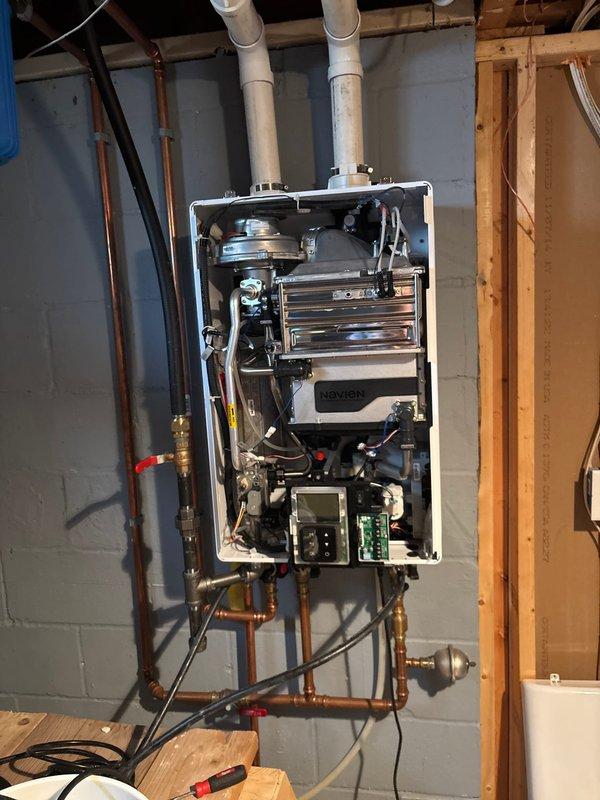 Responded to service call for Navien tankless water heater experiencing intermittent cold water delivery with unpredictable occurrence patterns. Unit had not been serviced since installation approximately 1-2 years prior. Upon inspection, performed complete descaling flush of heat exchanger using submersion pump and descaling solution to remove mineral buildup causing flow sensor irregularities and heat exchanger blockage. Opened unit's front access panel to inspect internal components, circuit boards, and heat exchanger condition. Flushed system thoroughly to restore proper water flow and consistent temperature delivery, resolving the cold water issue caused by scale accumulation on heating elements.