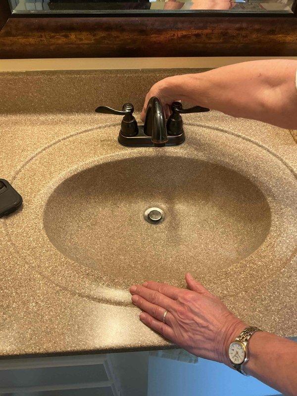 Responded to a leaking pop-up drain assembly at a bathroom sink faucet that had been dripping for approximately one month. Upon inspection of the 20-year-old fixture with dual-handle oil-rubbed bronze faucet and chrome pop-up drain, identified worn drain stopper seal as the source of the leak. Disassembled pop-up assembly, cleaned components, and replaced deteriorated gasket and stopper mechanism. Tested operation of pop-up drain and verified proper seal with no further leakage detected. Faucet handles and water flow functioning normally upon completion.