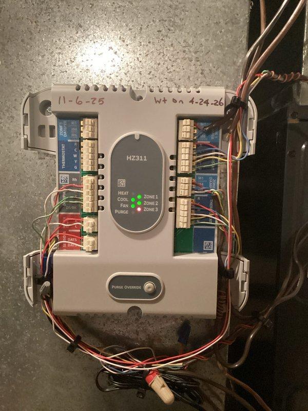 Responded to service call for air conditioning system not blowing or cooling to setpoint temperature. Upon arrival, inspected HZ311 zone control panel and found all three zones operational with proper LED indicators for heat, cool, and fan functions. Examined air handler unit and observed significant condensation accumulation on interior metal plenum surface, indicating active cooling operation but potential airflow restriction or inadequate system capacity. Verified condensate drain line installation and proper drainage. All zone control wiring connections secure at terminal blocks with no loose or damaged conductors noted. System appeared to be running but not achieving desired temperature, suggesting possible refrigerant charge issue, airflow deficiency, or thermostat calibration concern requiring further diagnostic evaluation.