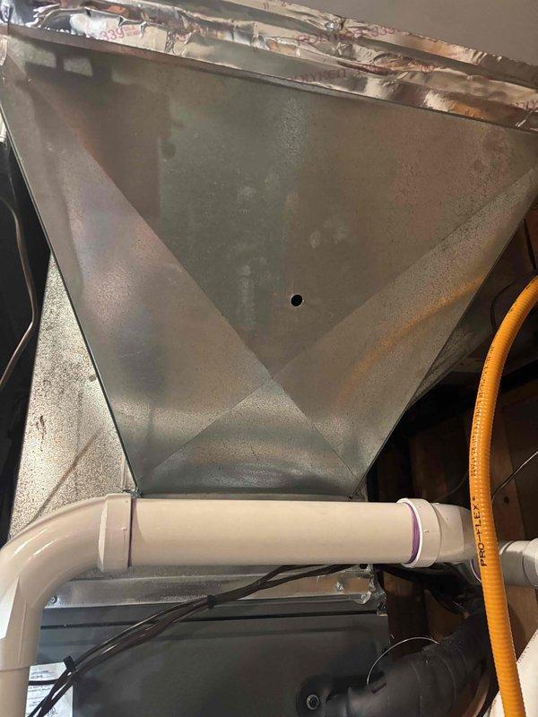 Responded to service call for air conditioning system not blowing or cooling to setpoint temperature. Upon arrival, inspected HZ311 zone control panel and found all three zones operational with proper LED indicators for heat, cool, and fan functions. Examined air handler unit and observed significant condensation accumulation on interior metal plenum surface, indicating active cooling operation but potential airflow restriction or inadequate system capacity. Verified condensate drain line installation and proper drainage. All zone control wiring connections secure at terminal blocks with no loose or damaged conductors noted. System appeared to be running but not achieving desired temperature, suggesting possible refrigerant charge issue, airflow deficiency, or thermostat calibration concern requiring further diagnostic evaluation.