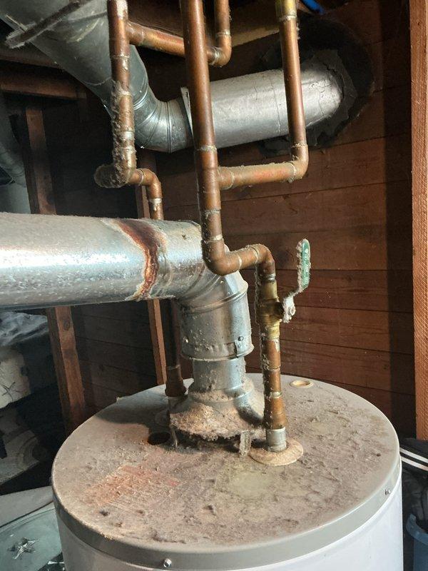 Responded to no hot water complaint on 16-year-old residential water heater. Upon inspection, found unit had reached end of serviceable life with significant sediment accumulation on top surface and aged plumbing connections showing mineral deposits and oxidation. Documented existing installation configuration including copper supply lines, pressure relief valve, and venting system in basement mechanical room. Customer advised of unit age and condition.