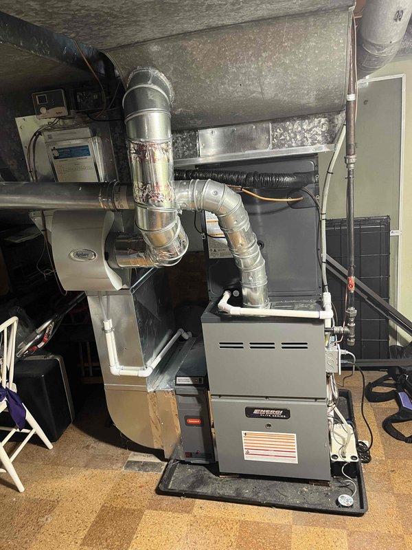 Completed full air conditioning system replacement in residential basement utility area. Installed new furnace unit on protective drainage pan with proper floor mounting, connected comprehensive metallic ductwork system including rigid and flexible sections with secure joints and transitions. Integrated air handler unit, established all necessary electrical connections, and verified proper routing of refrigerant lines and condensate drainage. All ductwork sealed at connection points, system tested for operational functionality, and installation completed per manufacturer specifications.