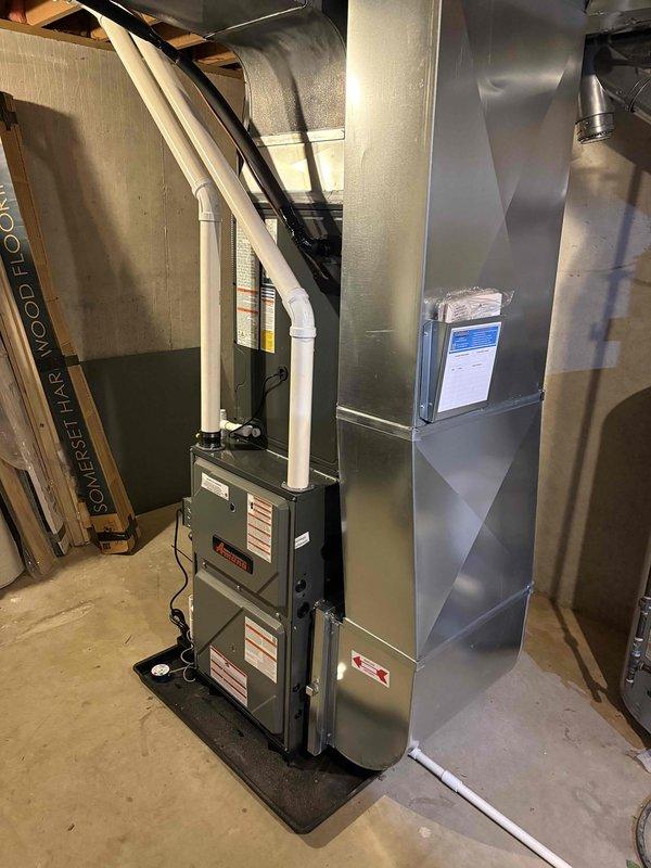 Completed full system replacement including installation of new high-efficiency furnace in basement utility area and matching outdoor condensing unit. Furnace installed on protective mat with proper venting via white PVC piping and connected to existing ductwork system. Outdoor unit positioned on concrete pad against exterior wall with electrical disconnect box mounted, refrigerant lines run through black flexible conduit, and all connections properly secured. All required documentation processed through Michigan Saves financing program and loan paperwork submitted electronically for approval.