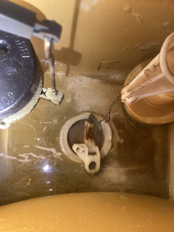 Responded to toilet flushing issue at residential property. Upon inspection, found aging flush valve assembly with worn flapper and compromised chain connection causing incomplete or irregular flushing cycles. Tank interior showed significant mineral deposits and water staining consistent with hard water conditions affecting component performance. Inspected fill valve assembly with float mechanism, which appeared functional but showed signs of age-related wear. Documented tank conditions including sediment buildup on interior surfaces. Photographed internal tank components and exterior toilet installation for service records. Recommended tank component replacement or adjustment to restore proper flushing function and prevent future performance issues.
