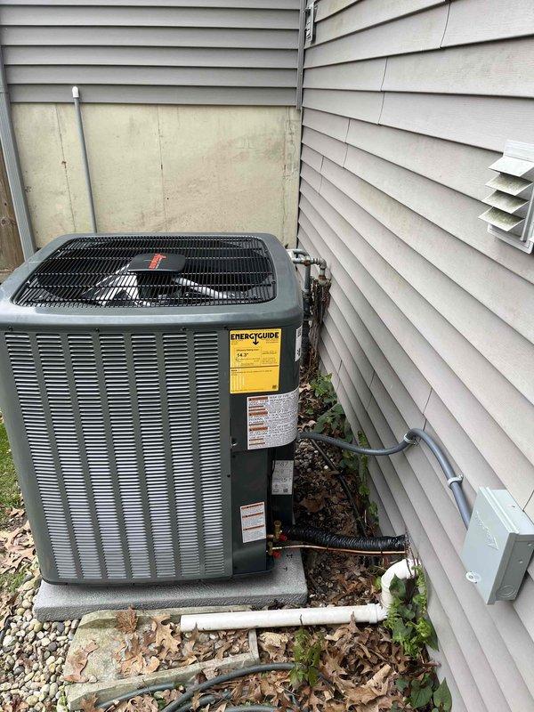 Completed full HVAC system installation including indoor air handler unit in basement utility area with new metallic ductwork runs and elbow connections. Installed outdoor condensing unit on concrete pad with proper gravel base, connected refrigerant lines and electrical disconnect box mounted to exterior wall. All components properly secured, labeled, and tested for operation per manufacturer specifications.