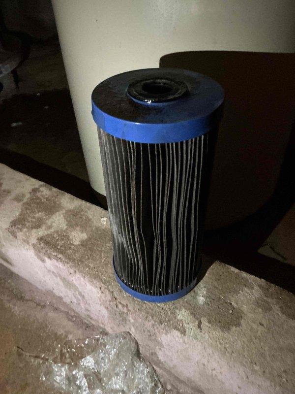 Responded to service call for whole home water filtration system maintenance. Successfully replaced B24 model filter cartridge in wall-mounted filtration housing. Removed used pleated filter element showing accumulated sediment and debris, installed new replacement cartridge, and reassembled blue cap housing to restore proper water filtration operation.