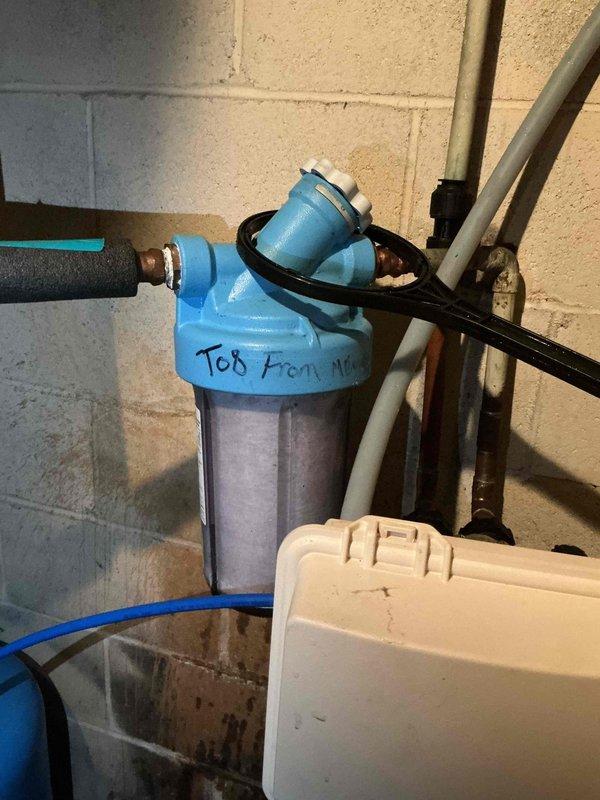 Responded to service call for whole home water filtration system maintenance. Successfully replaced B24 model filter cartridge in wall-mounted filtration housing. Removed used pleated filter element showing accumulated sediment and debris, installed new replacement cartridge, and reassembled blue cap housing to restore proper water filtration operation.