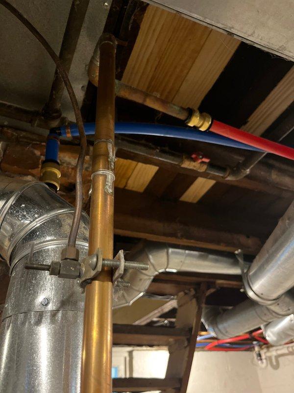 Responded to emergency call for water leakage behind residential water heater. Upon arrival, discovered pooling water at base of approximately 23-year-old water heater unit in basement utility area. Conducted thorough visual inspection of unit and surrounding plumbing infrastructure, including overhead copper supply lines, PEX connections, and associated piping. Documented existing conditions with photographs showing water heater installation, exposed plumbing system with multiple pipe materials (copper, PEX, flexible ductwork), and overall mechanical room configuration. Assessed age and condition of unit to determine source of leak and provided recommendations for necessary repairs or replacement given the advanced age of the equipment.