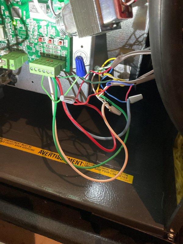 # No Cool Service Call

Responded to a no cooling complaint on a 20-year-old HVAC system. Upon inspection, found the unit blowing warm air. Accessed the control panel and examined the ComfortBridge circuit board, wiring connections, and associated components. Documented the internal control system configuration including the green circuit board with electronic components, terminal blocks, and color-coded wiring harness (red, green, blue, yellow, white, and brown conductors). Verified all wire connections at terminal blocks and wire nuts were secure. Inspected the blue capacitor mounted on the circuit board and checked refrigerant line connections visible in the upper cabinet area. Photographed the control panel assembly and wiring configuration for service records. System evaluated and customer advised of findings.