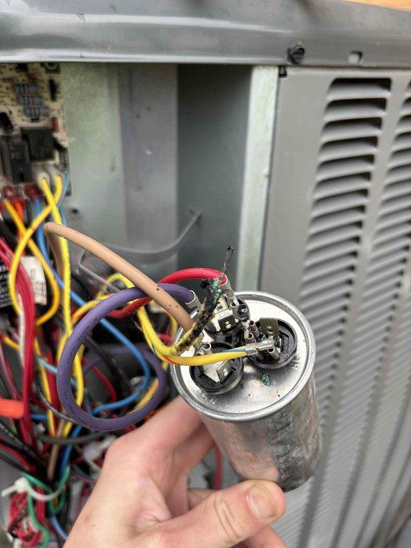 Responded to no-heat call on one-year-old heat pump system. Upon inspection, discovered failed dual run capacitor with severe heat damage and charring at terminal connections. Removed defective capacitor and installed new replacement unit, reconnected all wiring to proper terminals, and verified system operation with successful heat pump startup and normal heating cycle.