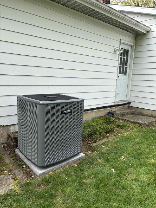 Successfully completed full HVAC system replacement including outdoor condensing unit and indoor air handling equipment. New gray condensing unit installed on existing concrete pad with proper clearances from foundation, connected to upgraded indoor components including furnace with integrated air handler. All refrigerant lines, electrical connections, condensate drainage via white PVC piping, and ductwork transitions properly installed and tested for optimal system performance.