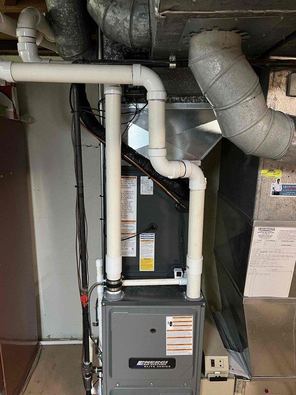 Successfully completed full HVAC system replacement including outdoor condensing unit and indoor air handling equipment. New gray condensing unit installed on existing concrete pad with proper clearances from foundation, connected to upgraded indoor components including furnace with integrated air handler. All refrigerant lines, electrical connections, condensate drainage via white PVC piping, and ductwork transitions properly installed and tested for optimal system performance.