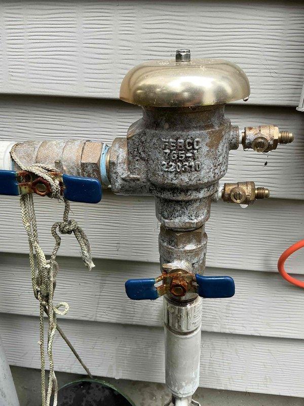 Responded to low water pressure complaint for irrigation system. Inspected exterior backflow preventer assembly and found significant corrosion and deterioration on the vacuum breaker device body and fittings. The weathered condition of the metallic components indicated prolonged outdoor exposure affecting system performance. Evaluated ball valve operation and brass outlet connections for proper flow capacity. Documented existing plumbing configuration including under-sink drain assembly for reference. Advised on backflow preventer condition and its impact on irrigation system pressure.