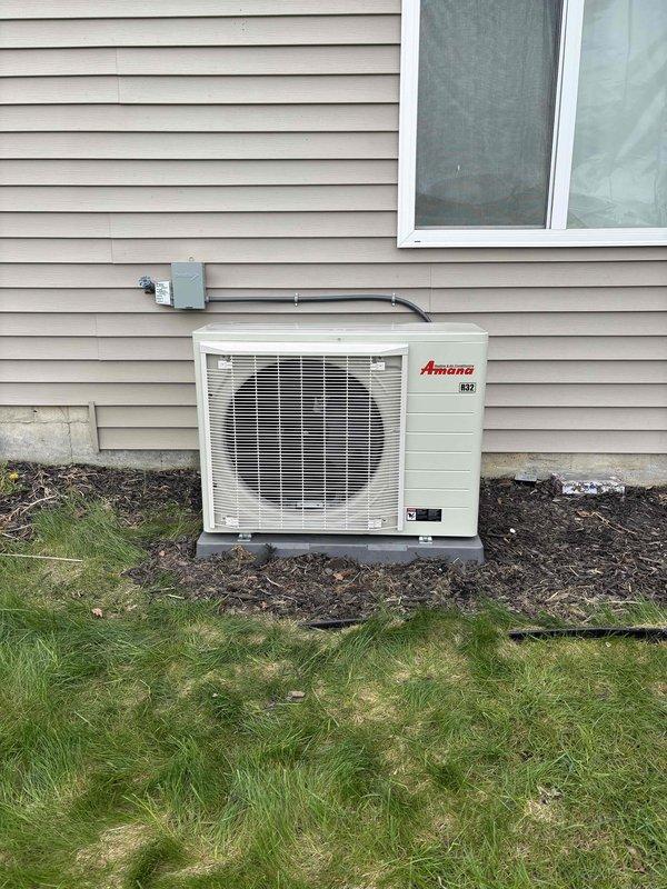Completed full HVAC system installation including new Amana outdoor condensing unit and high-efficiency furnace. Installed outdoor condenser on exterior wall with proper electrical disconnect box and conduit routing, positioned unit on ground-level pad with adequate clearance. Interior installation included furnace with complete ductwork connections, PVC condensate drainage and venting system, flexible supply ductwork, and new air filtration. All electrical connections, refrigerant lines, and mechanical systems tested and verified operational. System commissioned and ready for service.