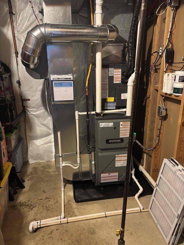 Completed full HVAC system installation including new Amana outdoor condensing unit and high-efficiency furnace. Installed outdoor condenser on exterior wall with proper electrical disconnect box and conduit routing, positioned unit on ground-level pad with adequate clearance. Interior installation included furnace with complete ductwork connections, PVC condensate drainage and venting system, flexible supply ductwork, and new air filtration. All electrical connections, refrigerant lines, and mechanical systems tested and verified operational. System commissioned and ready for service.