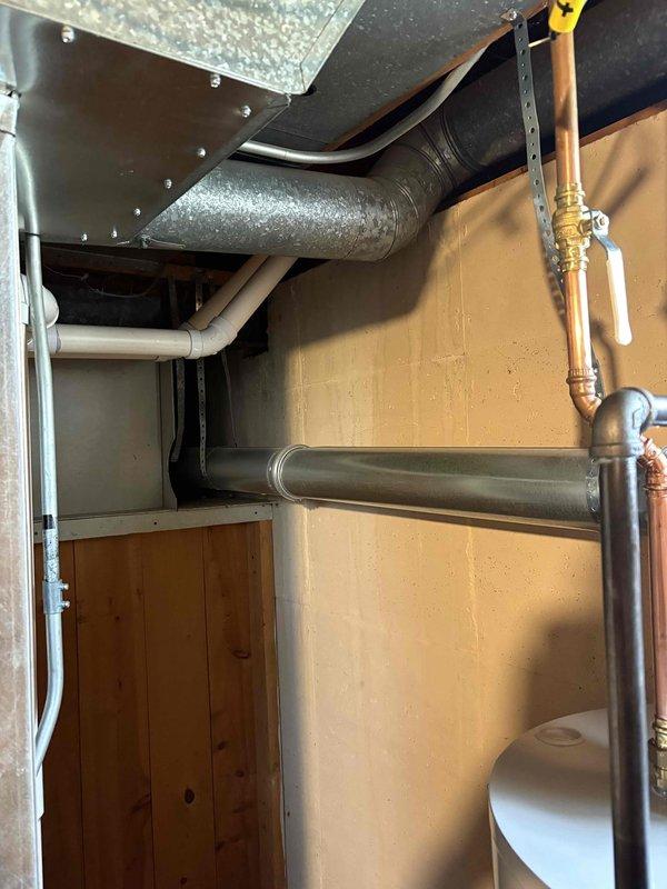 Successfully completed full water heater replacement in basement utility room. Removed existing unit and installed new cylindrical water heater with proper copper piping connections to overhead plumbing infrastructure. All connections were secured with appropriate brass fittings and valves, ensuring proper integration with existing HVAC ductwork and building systems in the mechanical space.