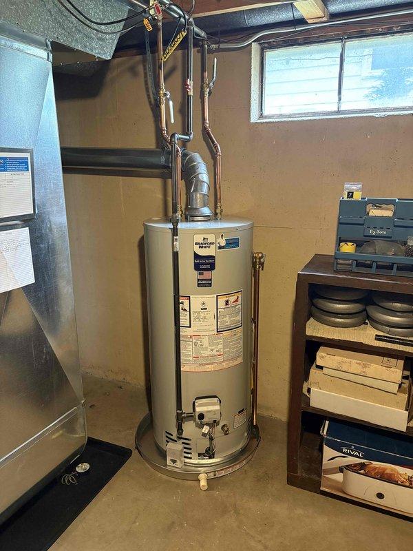 Successfully completed full water heater replacement in basement utility room. Removed existing unit and installed new cylindrical water heater with proper copper piping connections to overhead plumbing infrastructure. All connections were secured with appropriate brass fittings and valves, ensuring proper integration with existing HVAC ductwork and building systems in the mechanical space.