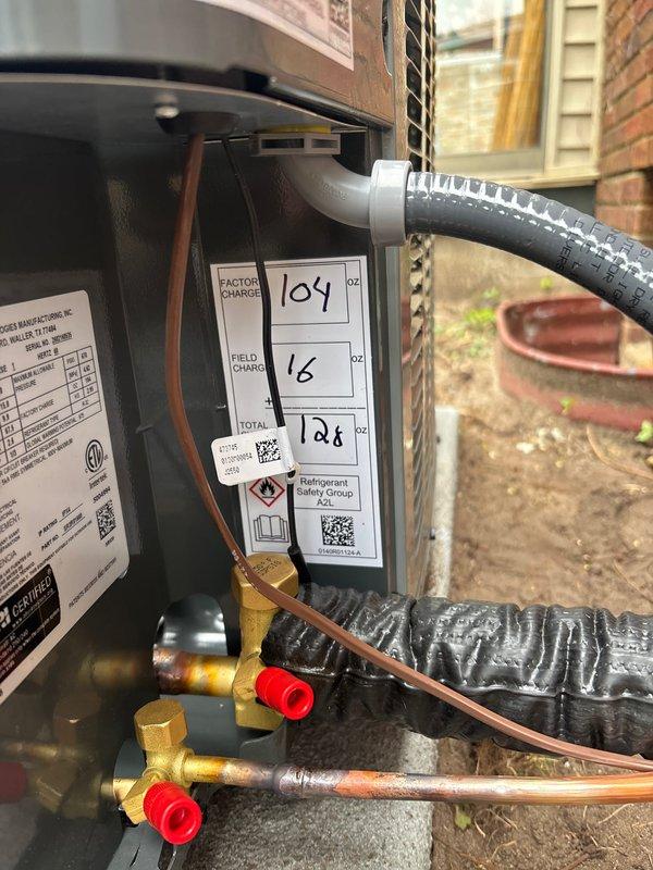 Completed full replacement of residential air conditioning system and water heater. Installed new Amana condenser unit on existing concrete pad with proper refrigerant line connections, electrical disconnect, and drainage provisions. System charged with A2L refrigerant per manufacturer specifications, with factory charge of 104 oz, field charge of 16 oz, for total system charge of 128 oz as documented on unit label.