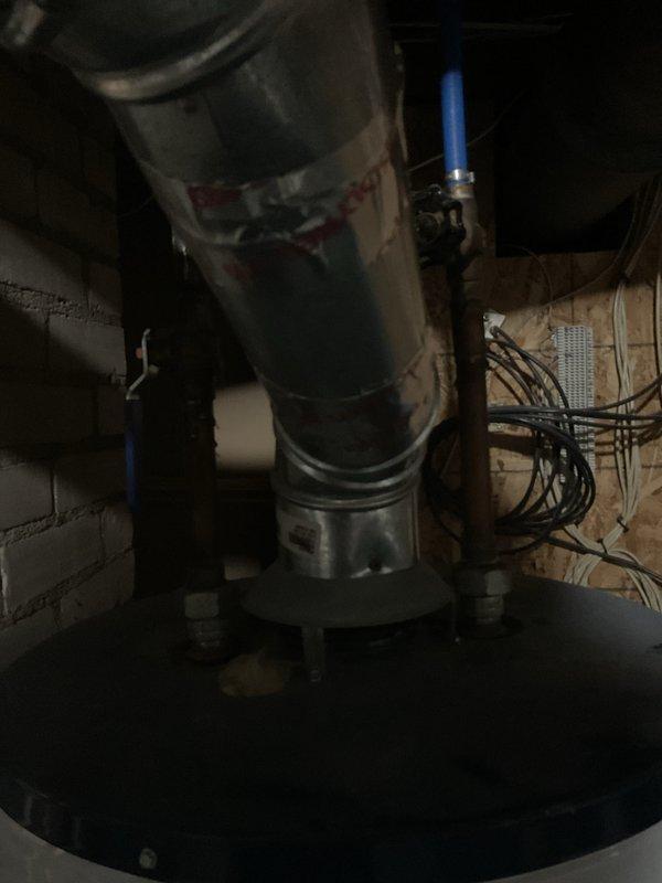 Conducted on-site evaluation for replacement of existing 16-year-old 40-gallon gas-fired water heater located in unfinished basement area with chimney venting configuration. Inspected current installation including gas supply lines, water connections with blue-handled shut-off valves, copper piping, electrical wiring, venting ductwork with condensation present, and concrete floor mounting location. Documented existing equipment condition, clearances, and accessibility for replacement purposes. Assessed chimney venting system compatibility and structural framing in utility space to provide comprehensive estimate for new water heater installation with proper venting, gas connections, and code-compliant setup.