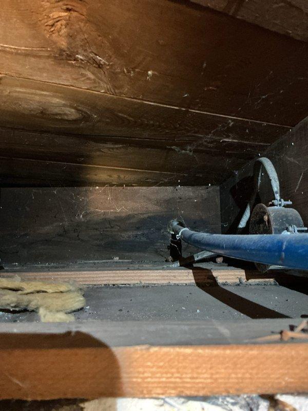 Responded to service call for outdoor spigot causing water overflow into basement when hose was attached. Accessed crawl space beneath structure to inspect plumbing connections and identify source of leak. Located blue PEX water supply line running to exterior faucet with compromised connection at metal coupling junction. Repaired faulty connection point where supply line met exterior spigot assembly, ensuring proper seal to prevent water from backing up into basement area when hose placed under pressure. Tested system with hose attached to verify no further overflow or leakage into crawl space. Work completed successfully with spigot now functioning properly without basement water intrusion.