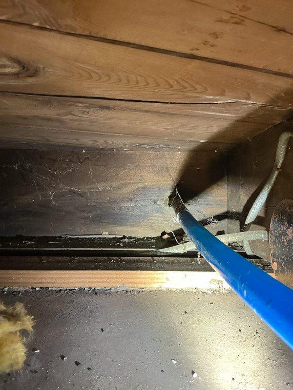 Responded to service call for outdoor spigot causing water overflow into basement when hose was attached. Accessed crawl space beneath structure to inspect plumbing connections and identify source of leak. Located blue PEX water supply line running to exterior faucet with compromised connection at metal coupling junction. Repaired faulty connection point where supply line met exterior spigot assembly, ensuring proper seal to prevent water from backing up into basement area when hose placed under pressure. Tested system with hose attached to verify no further overflow or leakage into crawl space. Work completed successfully with spigot now functioning properly without basement water intrusion.